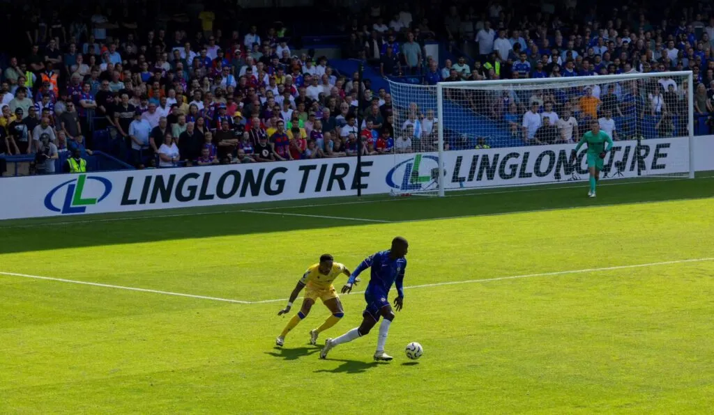 A Chelsea FC player dribbling the ball on the Stamford Bridge pitch in front of digital boards displaying the Linglong Tire logo. (Photo: Linglong Tire)