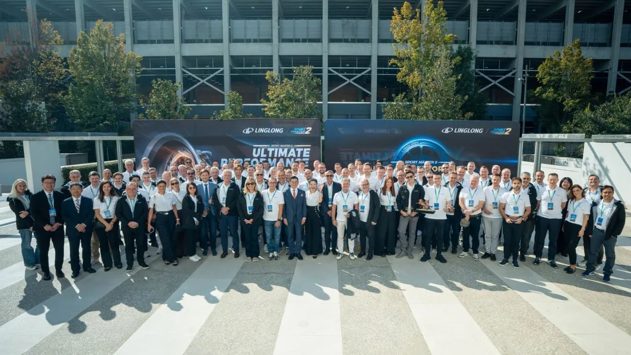 A large group of executives and dealers posing together outdoors in front of a dark backdrop with "Linglong Sport Master 2 Ultimate Performance" branding.