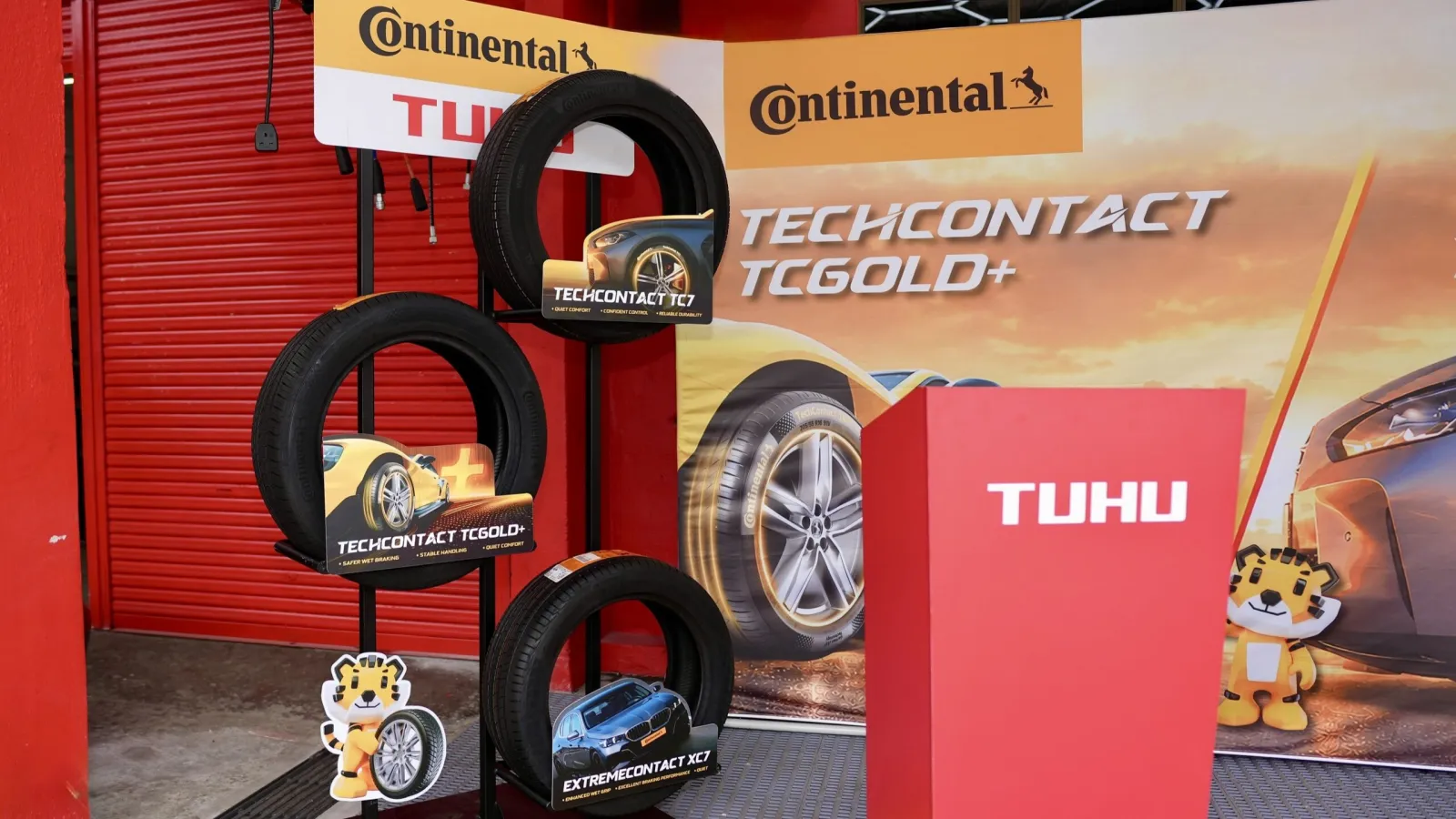 A black display stand holding three Continental tyres—the ExtremeContact XC7, TechContact TC7, and TechContact TC Gold Plus—positioned beside a red Tuhu podium.